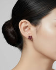Close-up of a woman wearing red floral earrings with a neutral background