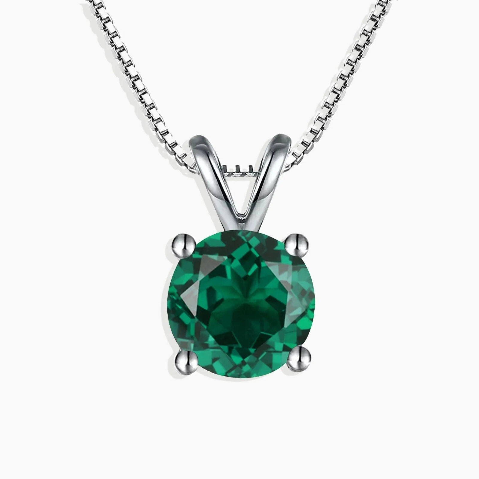 Sterling silver necklace featuring a round-cut emerald pendant on a white background.