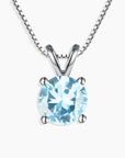 Close-up view of a round-cut aquamarine pendant set in silver with a classic prong design.