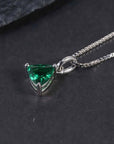 Close-up of the trillion-cut emerald pendant necklace displayed on a dark surface.