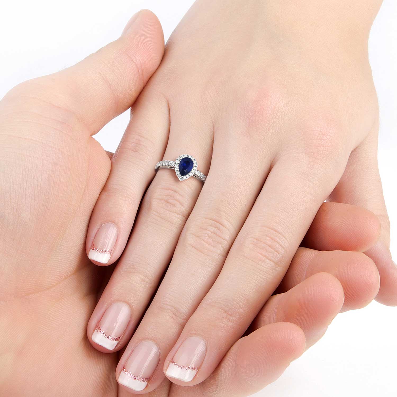 A mesmerizing sapphire pear-cut halo ring gracing a hand with its exquisite beauty and sophistication. The deep blue hue of the sapphire gemstone is enhanced by a halo of sparkling diamonds, evoking a sense of elegance and refinement.