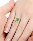 Hand wearing a Cushion Cut Peridot Halo Ring, showcasing the August birthstone in a luxurious Sterling Silver setting."