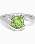 Close-up of round-cut peridot bezel ring in rhodium-plated sterling silver with minimalist band.