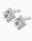 Front and angled side views of the square moissanite stud earrings, showing the round center stone and zirconia accents in a rhodium-plated setting.