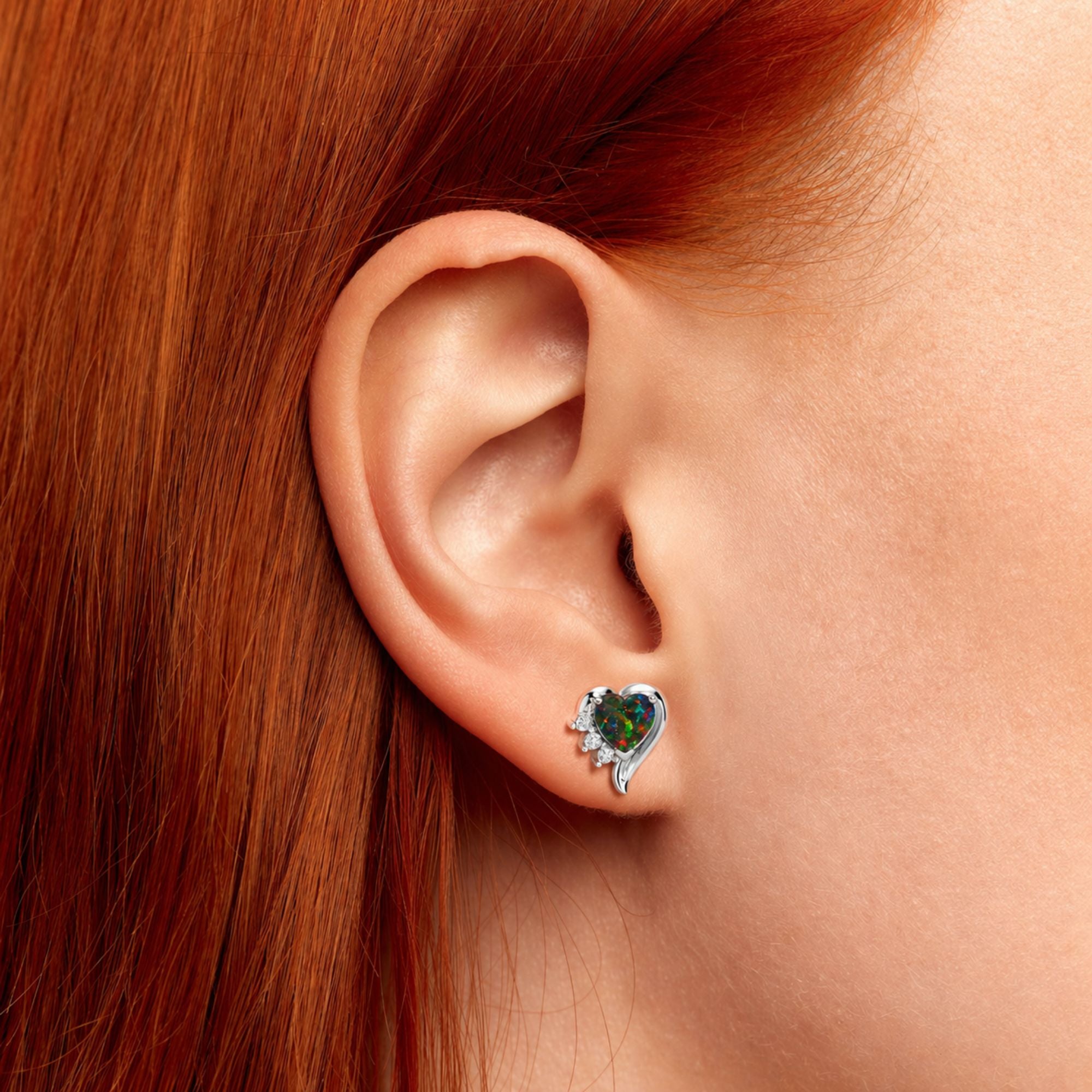 Close-up of an ear wearing a black opal gemstone earring with red hair.