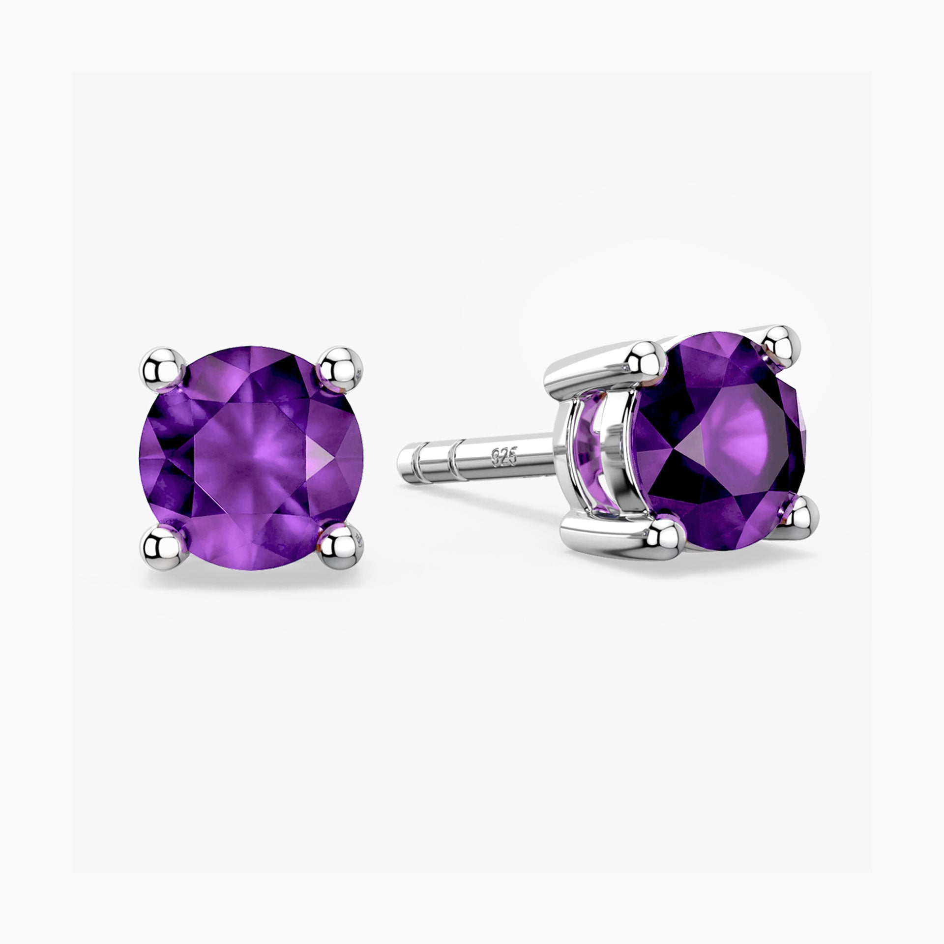Pair of sterling-silver amethyst stud earrings with round, faceted purple gemstones—one shown from the front and the other at an angle to reveal the four-prong setting—displayed on a white background