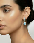 Close-up of a woman wearing a blue gemstone earring with a neutral background