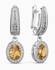 Pair of silver earrings with yellow citrine gemstones on a white background