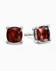 Cushion-cut garnet stud earrings in sterling silver four-prong setting, featuring deep red gemstones.