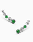 Sterling silver climber earrings featuring round emeralds and diamond stimulants in a floral design.