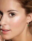 Side portrait of a woman wearing the oval emerald hoop drop earrings, illustrating the earrings’ size and elegant style.