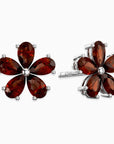 Flower-shaped earrings with red garnet gemstones on a white background