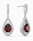 Teardrop-shaped earrings with red garnet gemstones and diamond accents on a white background