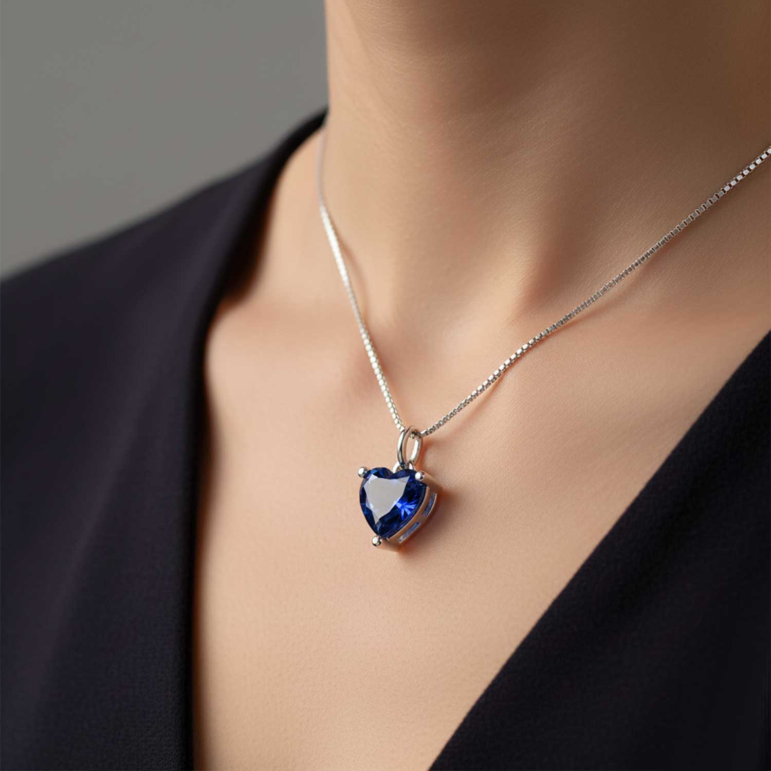 Heart-shaped blue gemstone necklace on a person wearing a black top.