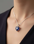 Heart-shaped blue gemstone necklace on a person wearing a black top.