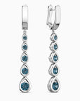 Pair of silver earrings with blue topaz gemstones on a white background