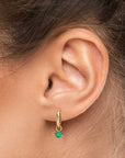 Woman wearing the 18K gold-plated emerald charm hoop earrings, showcasing their vibrant green gemstones and sleek hoop design.