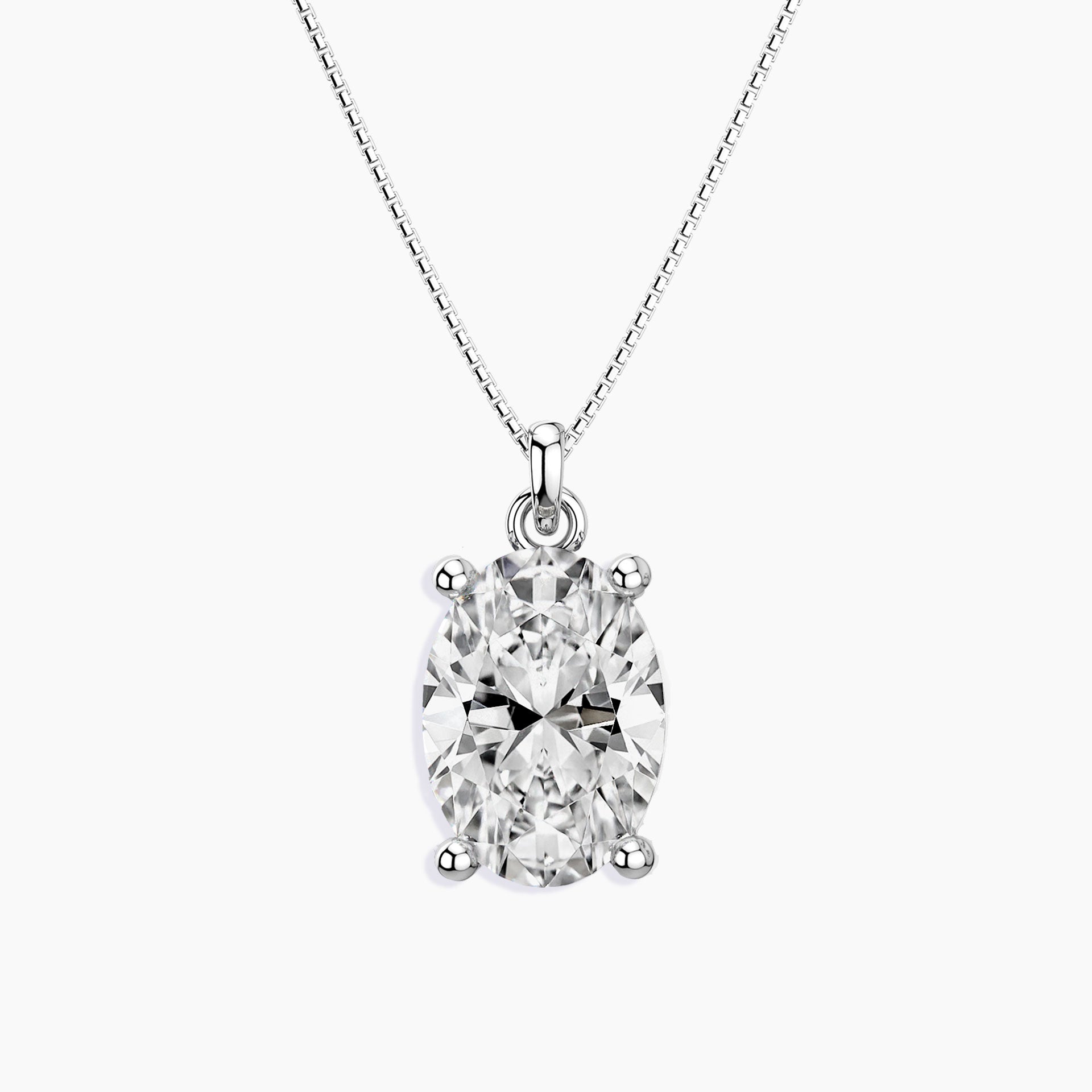 Oval-cut clear gemstone pendant in a four-prong silver setting, suspended from a fine silver chain, displayed on a white background.