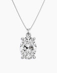 Oval-cut clear gemstone pendant in a four-prong silver setting, suspended from a fine silver chain, displayed on a white background.