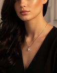 Woman wearing a black top with a silver emrald cut moissanite pendant.