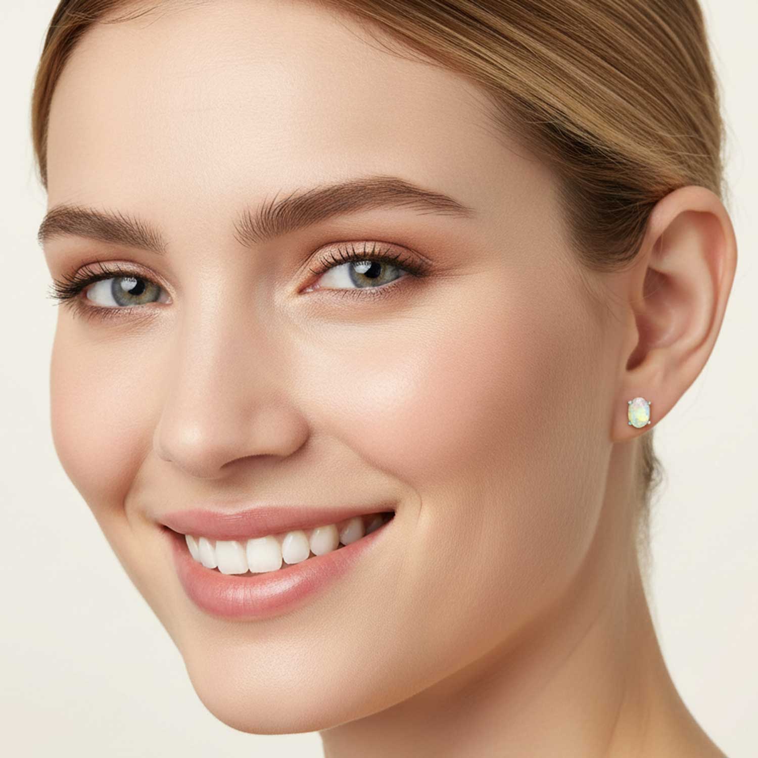 Close-up of a woman's face wearing a gold earring with a green gemstone on a beige background