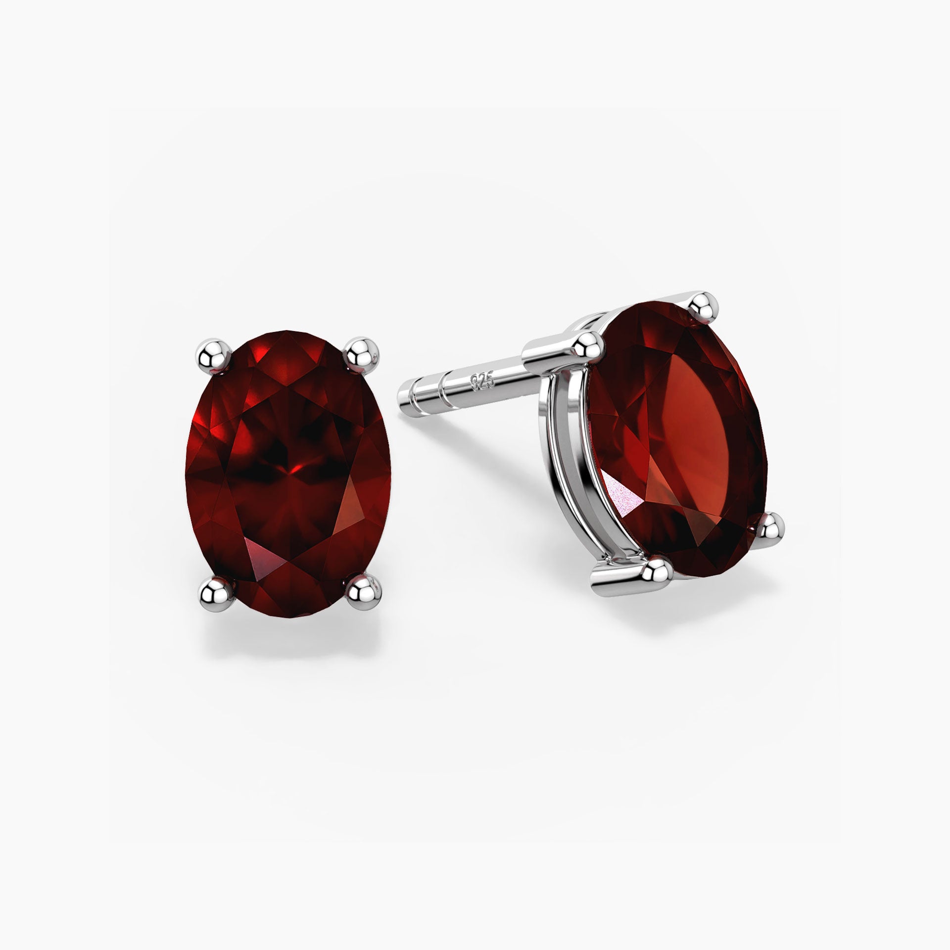 Pair of oval-cut deep red garnet stud earrings set in silver prong settings with push-back closures, displayed on a white background.