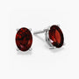 Pair of oval-cut deep red garnet stud earrings set in silver prong settings with push-back closures, displayed on a white background.