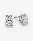 Pair of oval-cut clear gemstone stud earrings in a four-prong silver setting with push-back closures, displayed on a white background.