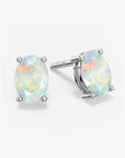 Pair of oval-cut white opal stud earrings with iridescent rainbow flashes, set in four-prong silver settings with push-back closures, displayed on a white background