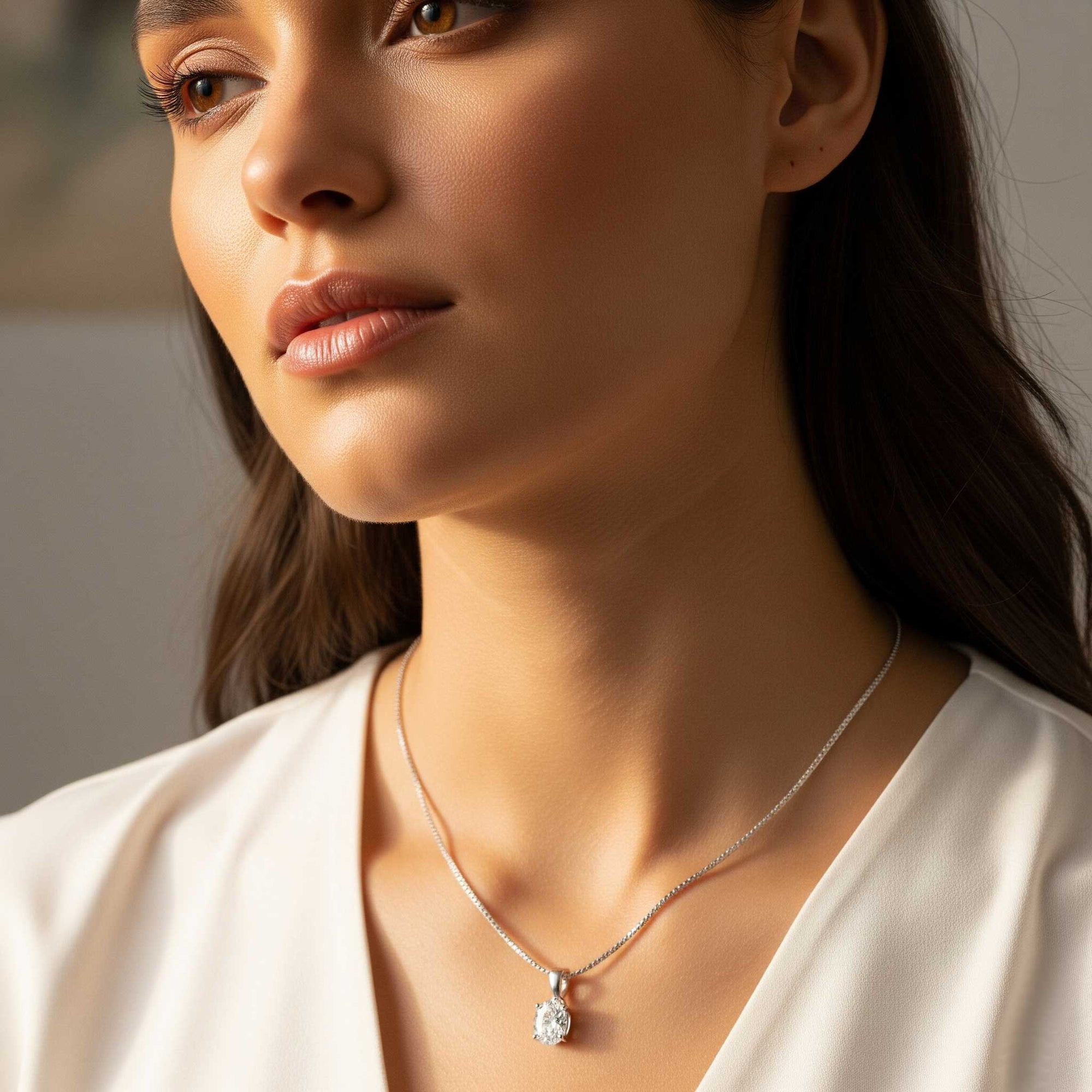 Close-up of a woman wearing a silver necklace with a pendant.