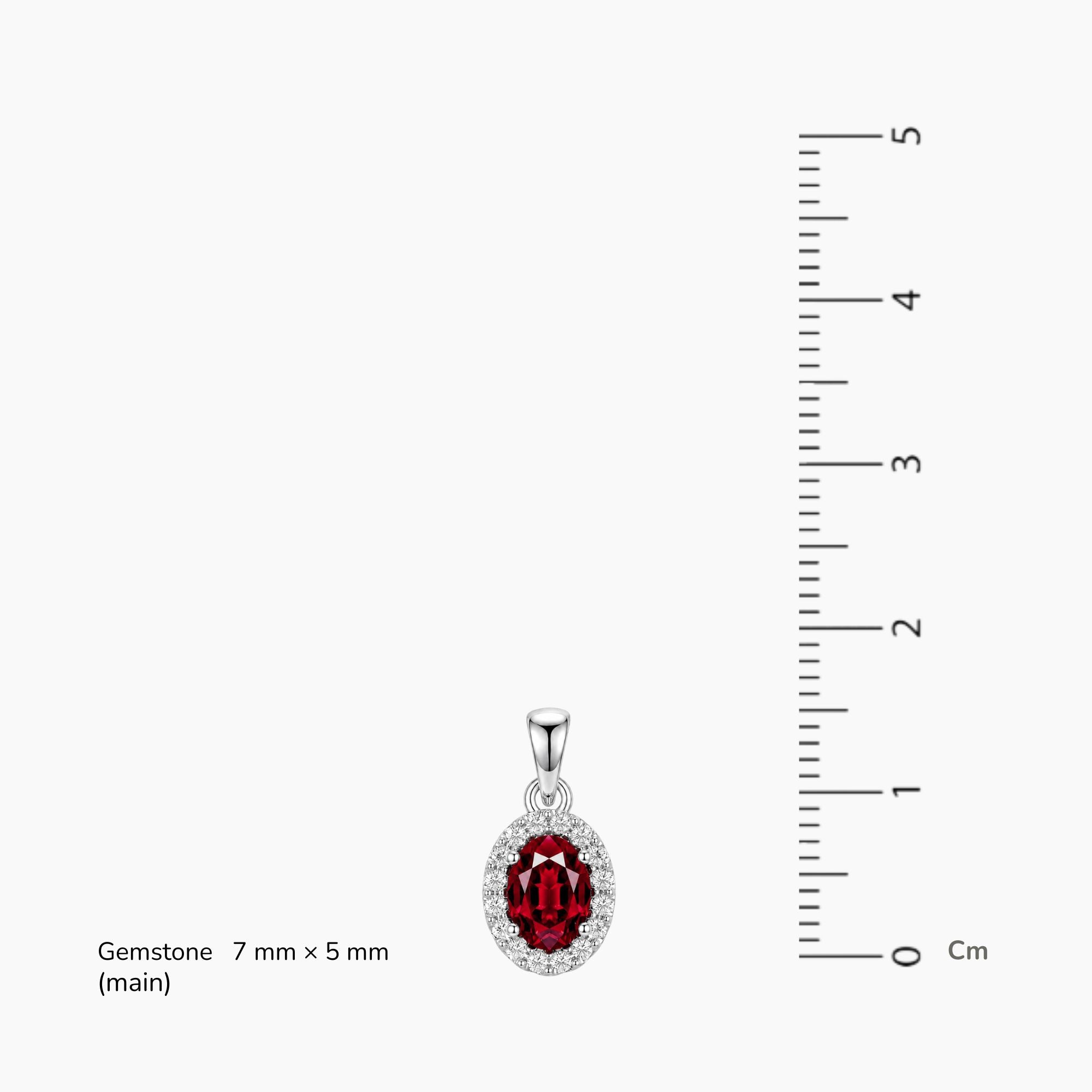 Silver pendant with a red ruby oval halo gemstone next to a ruler on a white background