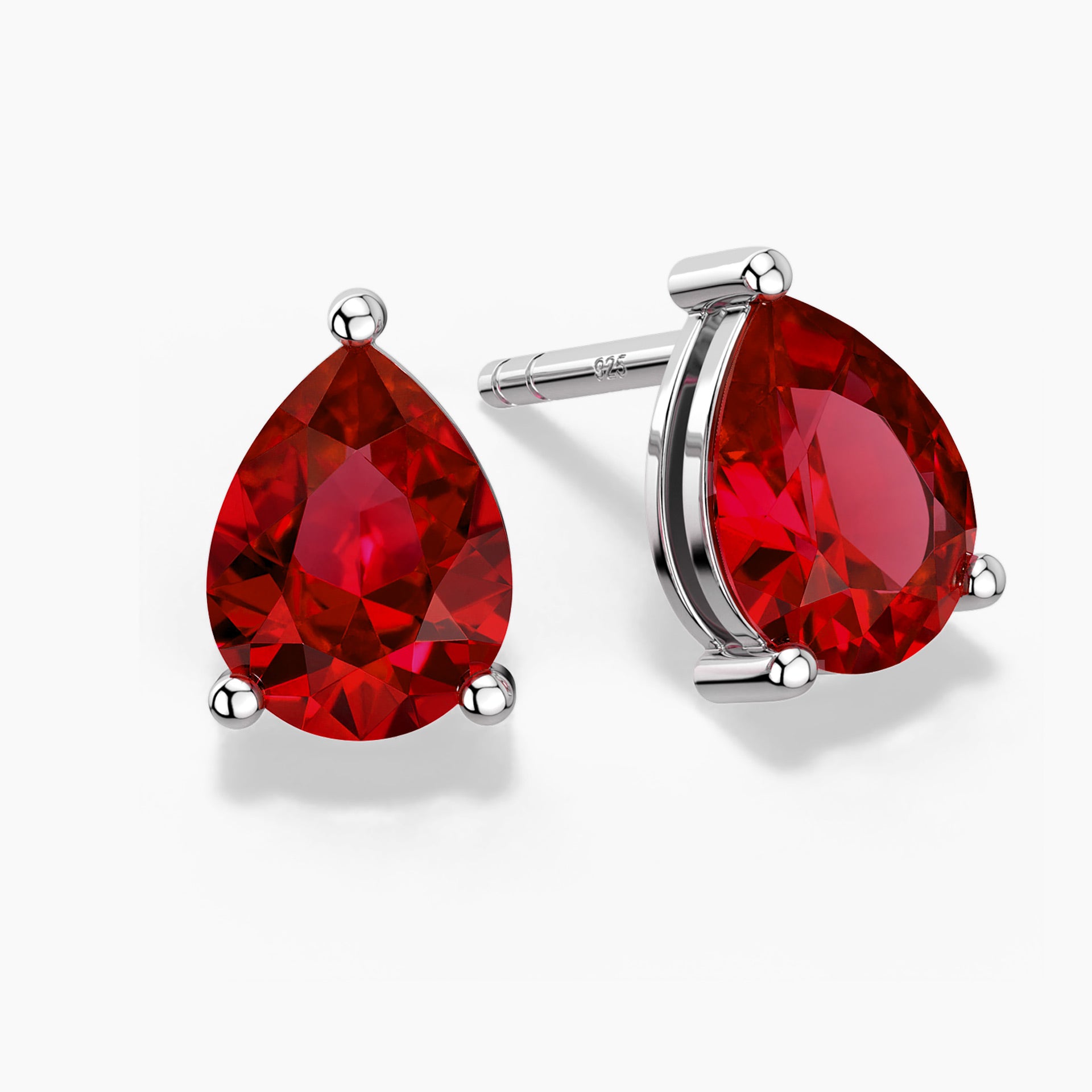 Two pear-shaped deep red gemstones set as sterling silver stud earrings, one shown head-on and the other at a slight angle, each held by three polished prongs on a clean white background.