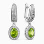 Pair of earrings with green gemstones and silver accents on a white background