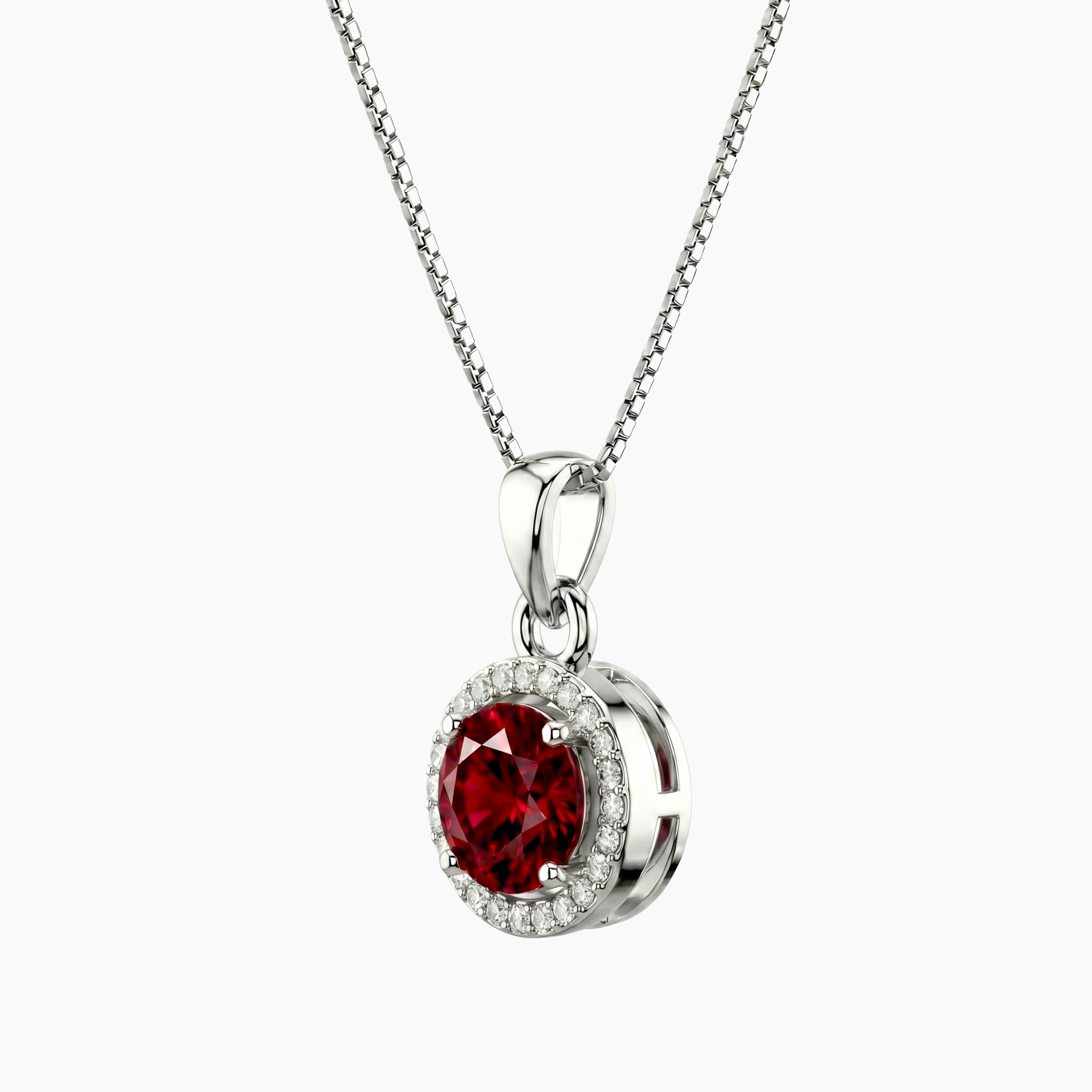 Silver pendant with a red round ruby gemstone with halo side profile on a white background