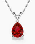 A pear-shaped deep red gemstone pendant set in polished sterling silver, hanging from a delicate silver chain against a white background.