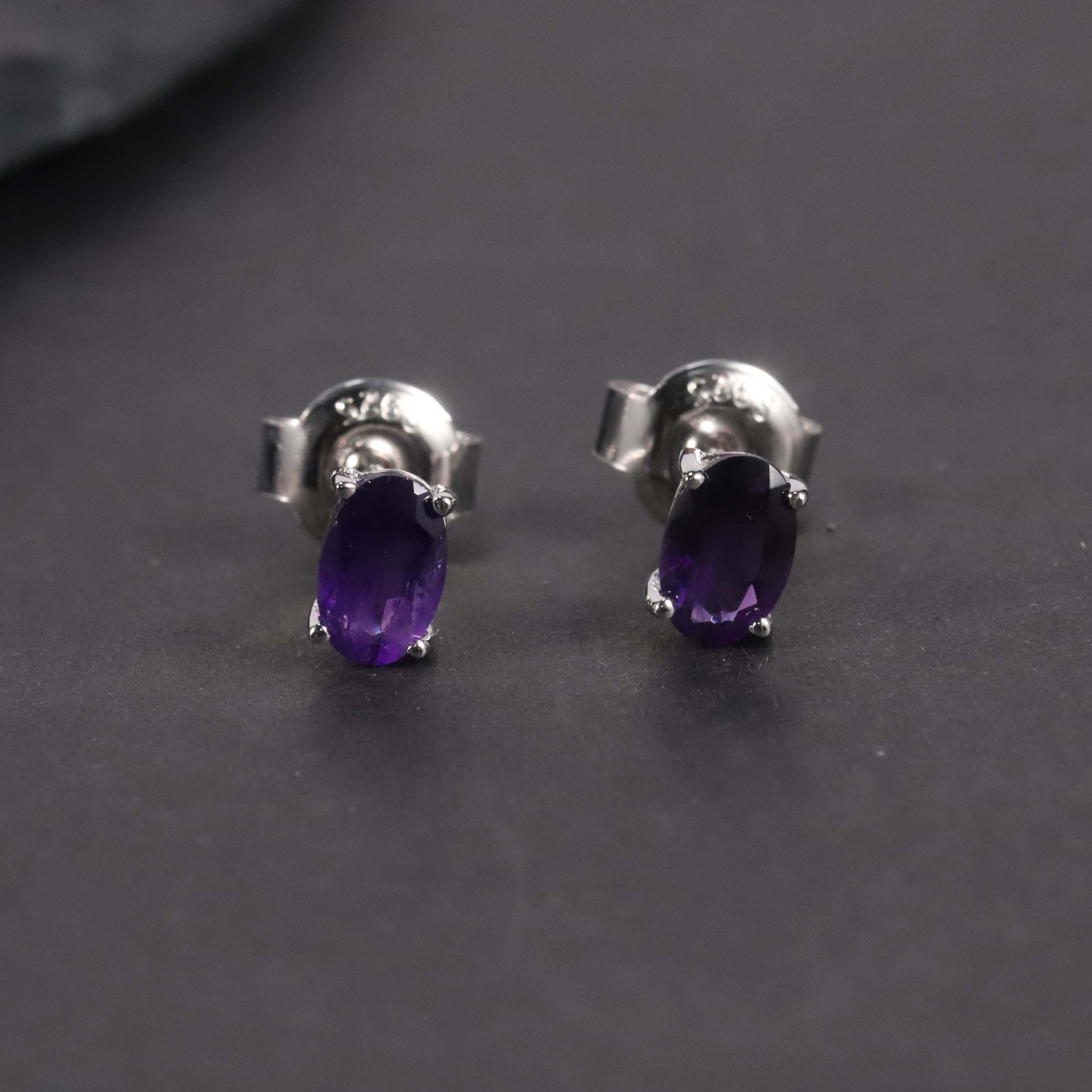 front view of amethyst oval studs on dark background