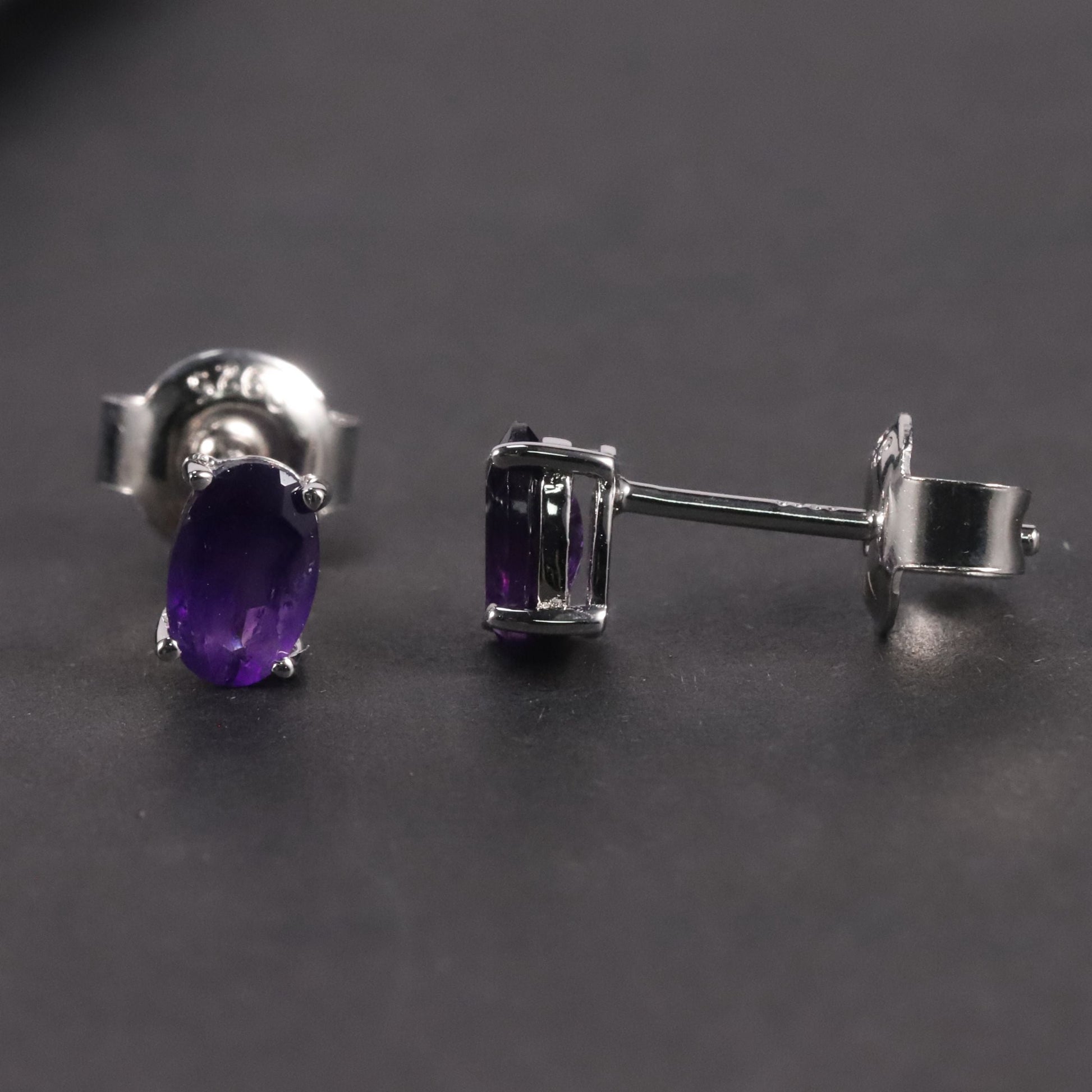 Side view of the Amethyst Oval Stud Earrings against a dark background, accentuating their exquisite design and craftsmanship.