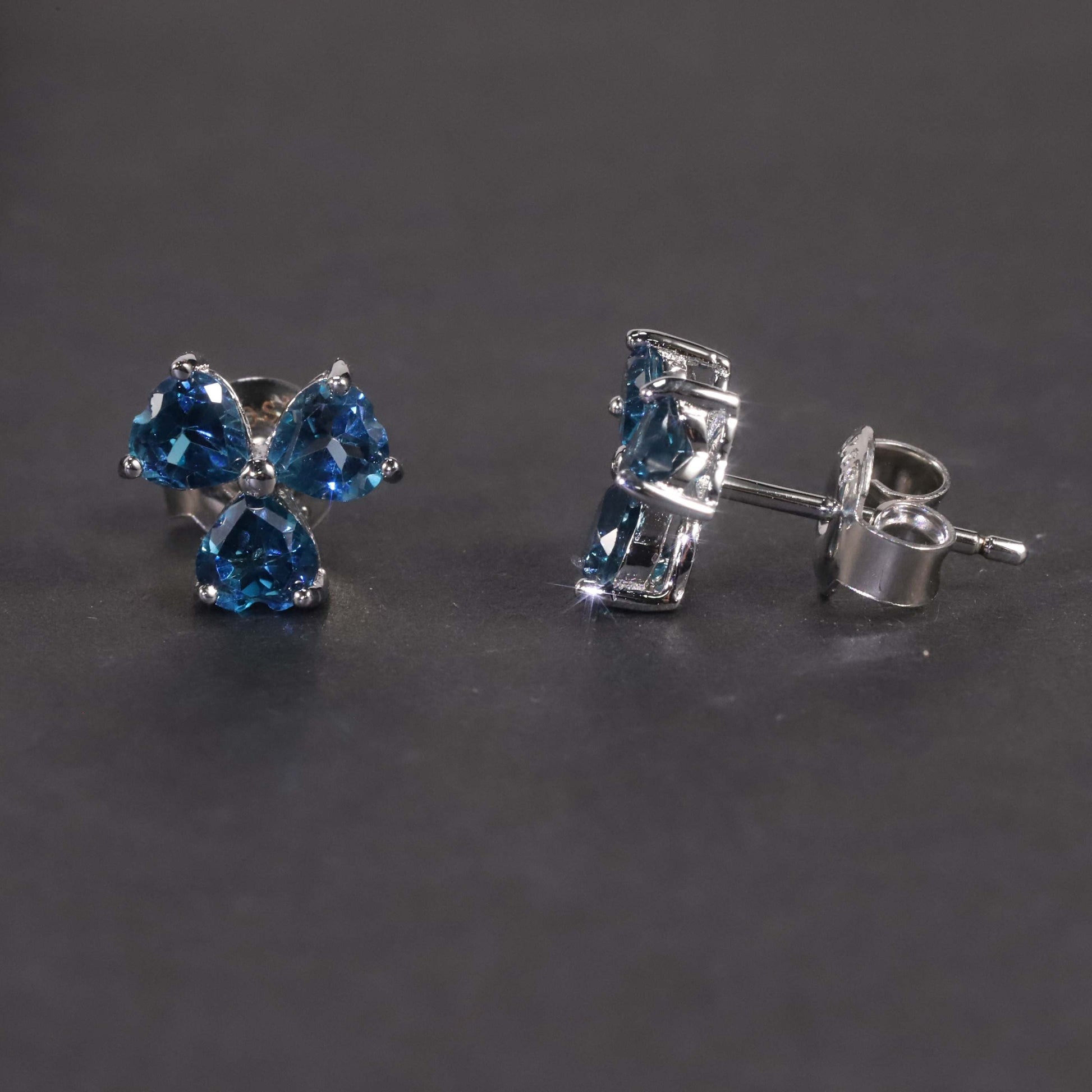 Side view on dark background of flower-shaped silver London blue topaz jewellery